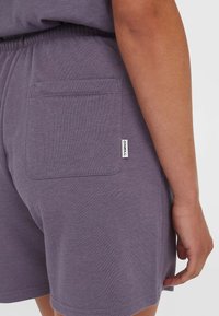Paarse shorts van zacht materiaal, met een achterzak en een klein merkembleem. Elastische tailleband met een relaxte pasvorm.