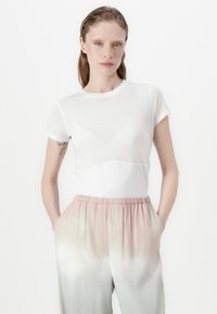 White short-sleeve t-shirt with a sheer overlay; paired with loose, gradient trousers transitioning from pale pink to light green.