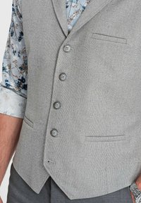 Gray textured vest with five buttons, two front pockets, and a pointed hem. Features a light blue floral shirt underneath.