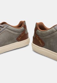 Grijze canvas schoenen met bruine leren accenten en beige rubberen zolen. Voorzien van een vetersluiting en een reliëf 'Est. 1894' detail.