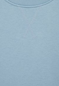 Gaiši zils džemperis ar ribotu apkakli un X formas šuvuma detaļām aizmugurē. Izgatavots no mīksta, teksturēta adījuma auduma.