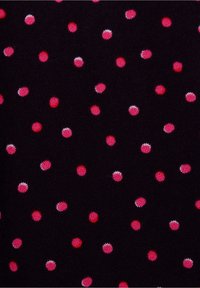 Schwarzer Stoff mit einer strukturierten Oberfläche zeigt ein wiederholendes Muster aus pinken und roten Punkten in unterschiedlichen Größen.
