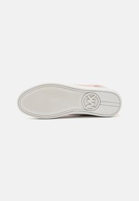 Suola di una sneaker rosa chiaro con grip testurizzato e logo circolare in rilievo "MK" vicino al tallone su sfondo bianco.