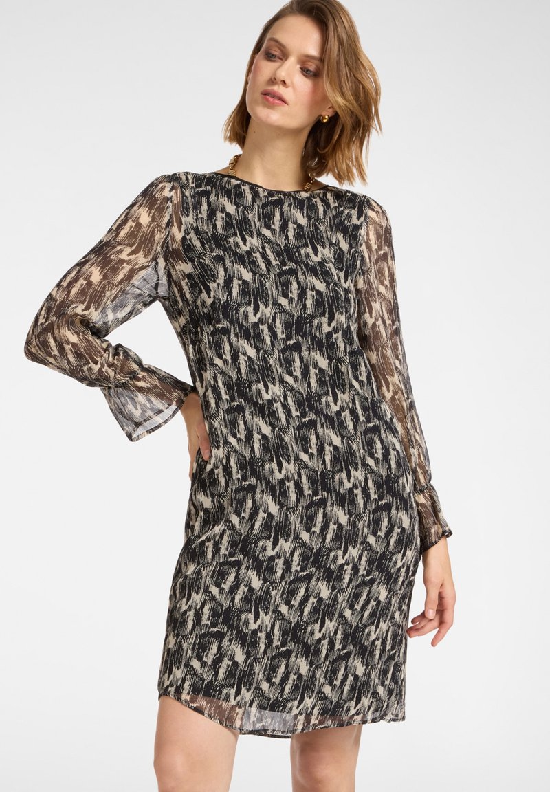 Kleid mit kurzen Ärmeln und fließendem Design, das mit einem schwarz-weiß-cremefarbenen abstrakten Muster versehen ist und aus leichtem Stoff gefertigt wurde. Betonte Ärmel und ein runder Ausschnitt.