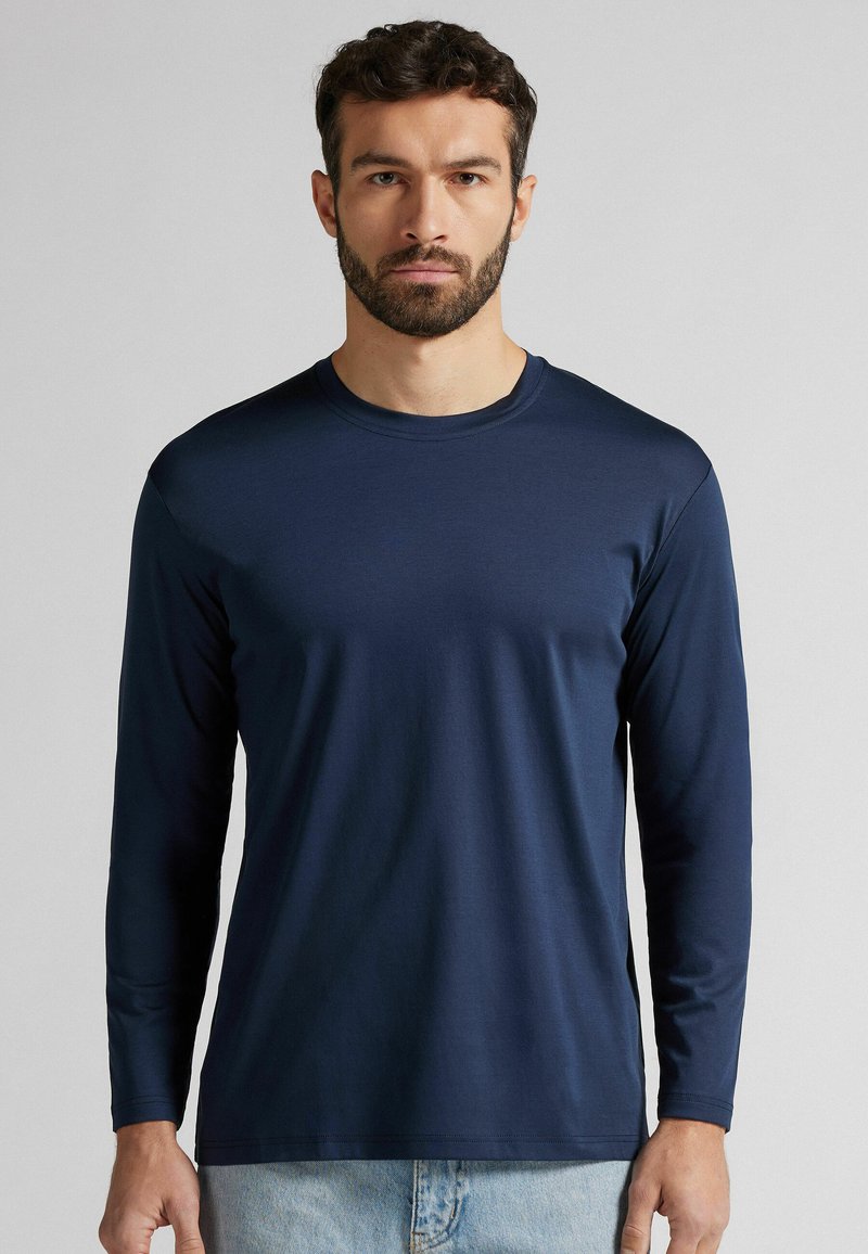 Maglietta a maniche lunghe blu navy realizzata in tessuto morbido con scollo rotondo e design fitted, caratterizzata da maniche lunghe e orlo dritto.