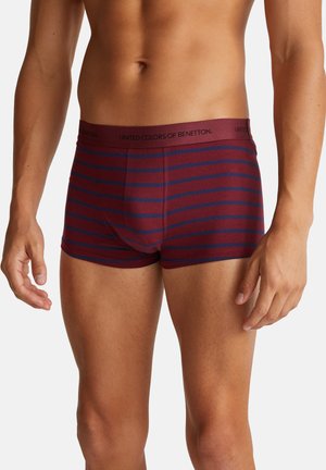 Des boxers en tissu doux, présentant des rayures horizontales bordeaux et bleu marine, avec une taille unie bordeaux portant l'inscription "United Colors of Benetton."