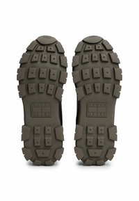 Suola esterna in gomma nera dal design robusto, con tacchetti pronunciati e un logo rettangolare "TOMMY JEANS" al centro.