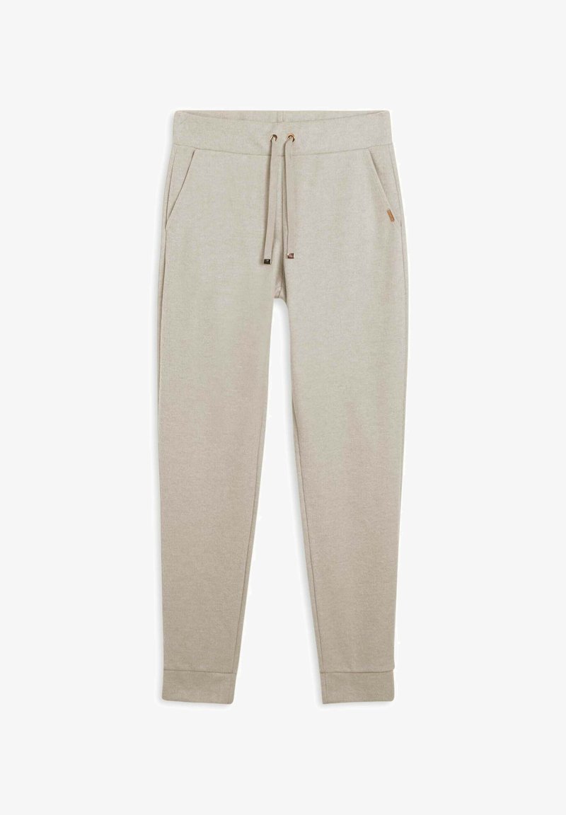 Pantalones jogger en beige claro hechos de tela suave, con cintura ajustable con cordón, dos bolsillos laterales y puños acanalados. Sutil detalle de logo en la cintura.