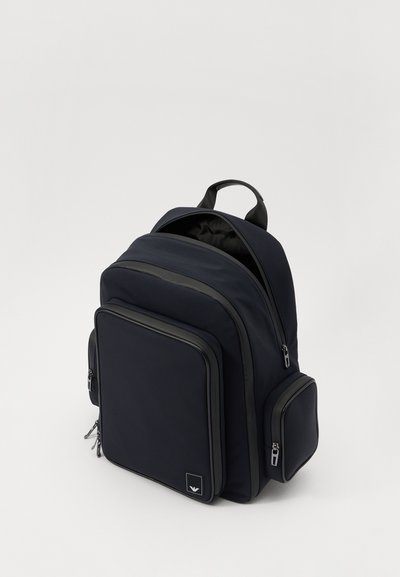 Ναυτικό σακίδιο πλάτης από υφασμάτινη υφή με κύρια θήκη, μπροστινή τσέπη και πλαϊνή τσέπη. Διαθέτει κλείσιμο με φερμουάρ και λαβή στο επάνω μέρος.