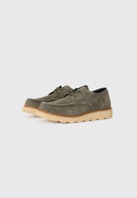 Olive green suede shoes with a rounded toe, beige rubber sole, and tonal laces. Stitching detail along the upper adds texture.