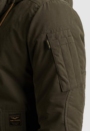 Giacca verde oliva con tessuto testurizzato, molteplici tasche e una toppa con la scritta "PME Legend". Il design include cuciture rinforzate sulle spalle.