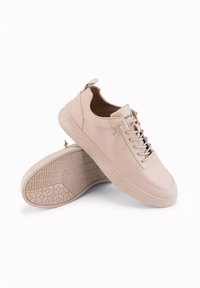 Baskets en cuir rose clair avec une semelle en caoutchouc texturée, un design à lacets et un petit tirant à l'arrière. Style épuré et minimaliste.