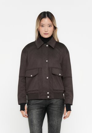 Dark brown jacket with a high collar, front snap buttons, two large patch pockets, and ribbed cuffs. Smooth fabric texture.