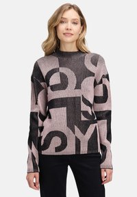 Strickpullover mit gerippter Textur, schwarz-rosa Farbschema und auff�älligen grafischen Buchstaben. Lange Ärmel und hoher Kragen.