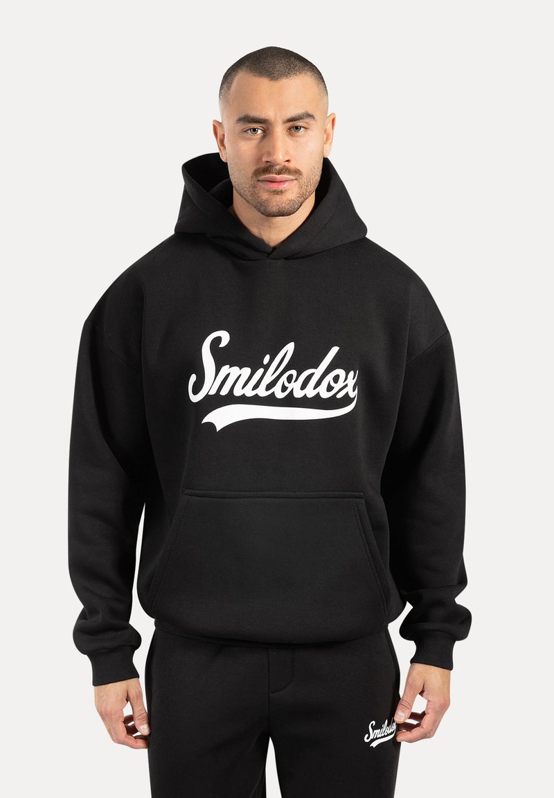 Sudadera negra con capucha hecha de una mezcla de algodón, que presenta un logo blanco de "Smilodox", un bolsillo canguro y puños de canalé. Combinada con pantalones negros a juego.