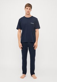 Mørkeblå bomulds t-shirt med korte ærmer og rund hals, med et lille logo. Sammen med matchende mørkeblå bukser.