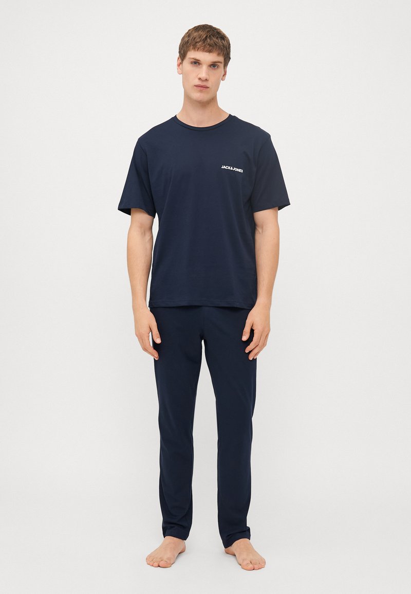 Mørkeblå bomulds t-shirt med korte ærmer og rund hals, med et lille logo. Sammen med matchende mørkeblå bukser.