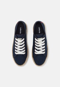 Navy canvas sneakers with white laces, featuring a jute rope sole. Brand label visible inside; simple design with a round toe shape.