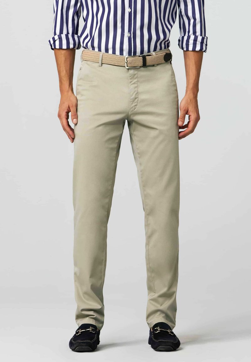Light beige chinos with a straight cut, made from cotton blend fabric. Styled with a woven tan belt and dark loafers. Vertical striped shirt visible.