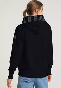 Schwarzer Hoodie mit einem großen grauen Logo auf der Kapuze, aus weichem Stoff, mit lässigem Schnitt und gerippten Bündchen. Rückansicht gezeigt.