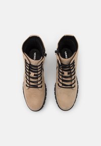 Botas de tobillo de ante marrón con cordones negros, superficies texturizadas y suela de goma. Cuentan con un cierre de cremallera y un cuello acolchado para mayor comodidad.