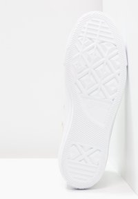 Biała gumowa podeszwa buta z geometrycznym wzorem bieżnika i wypukłymi akcentami. Posiada wyraźne oznaczenie "Converse All Star".