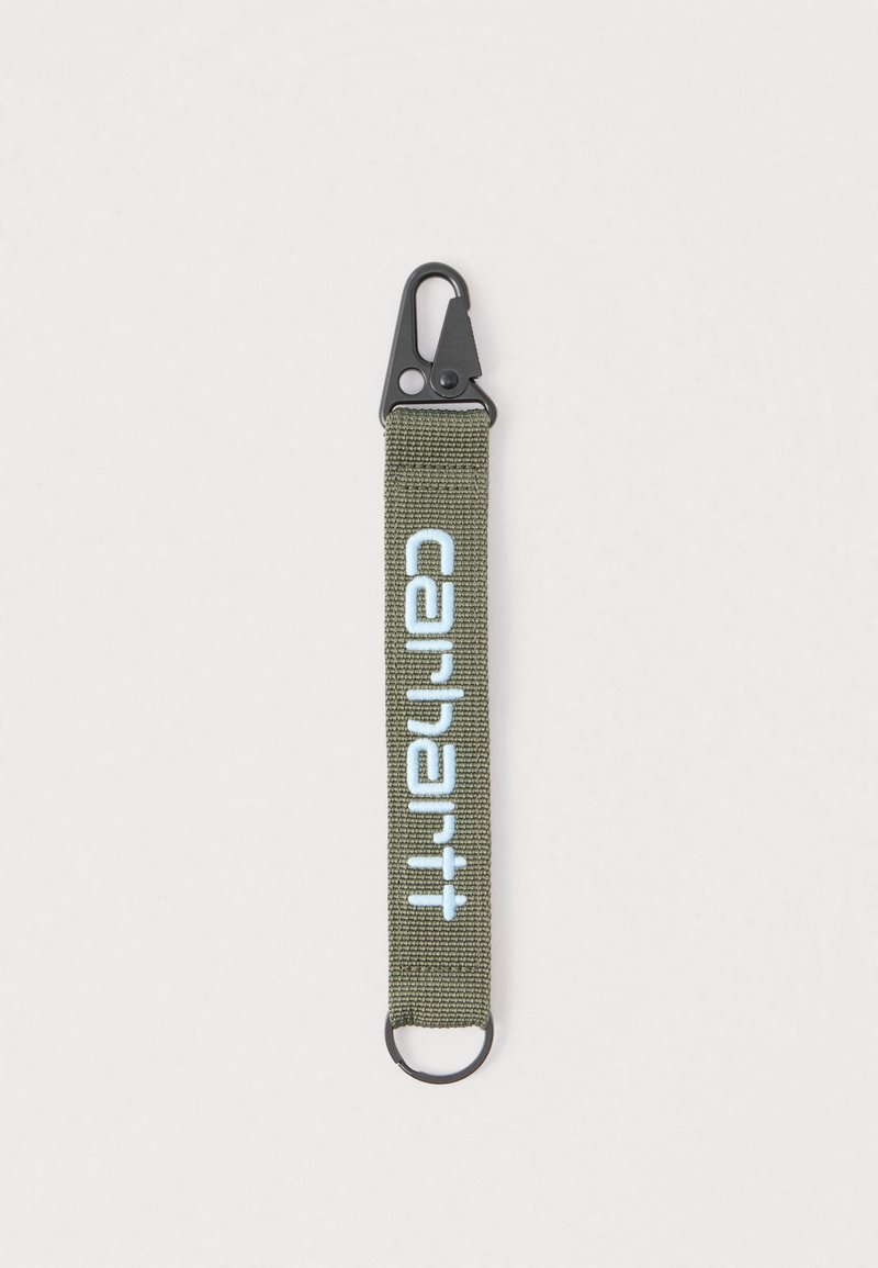 Λουρί μπρελόκ από ελιά πράσινο ύφασμα με μαύρο κλιπ και ασημένιο δαχτυλίδι, με ετικέτα "carhartt" σε ανοιχτό μπλε καλλιγραφικό κείμενο.