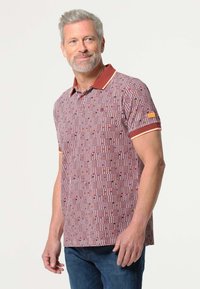 Korte mouw polo-shirt in bordeaux met een geometrisch patroon. Voorzien van een effen kraag en manchetten met contrasterende bies. Casual pasvorm.