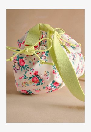 Lille õiemustriga kott, millel on kreemjas taust ja roosa ning roheline muster. Includes figuring features light yellow accents ja kootud õlarihm.