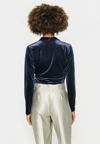 Navy blue velvet long-sleeve top with a smooth texture, paired with high-waisted light gray satin trousers featuring a subtle sheen.