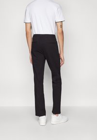 Černé bavlněné kalhoty slim fit. Kombinují se s bílým tričkem a bílými teniskami. Mají kapsy a čistý design.