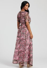 Maxiklänning i genomskinlig rosa tyg med ett bladmönster. Har korta ärmar, en insydd midja och en flödande silhuett. Bärs med platåklackar.