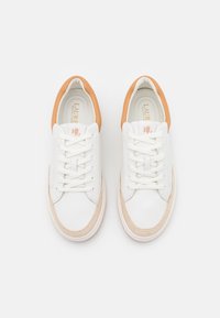 Sneakers bianchi in pelle con accento in pelle color cuoio sul tallone, caratterizzati da lacci bianchi, punta arrotondata, pannello laterale beige e un discreto dettaglio del logo sulla linguetta.