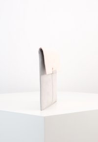 Szara i różowa kopertówka z eko-skóry o gładkiej fakturze i prostym, minimalistycznym wzornictwie. Czyste krawędzie bez widocznych elementów metalowych.