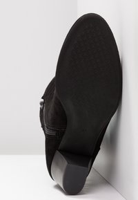 Bottines en suede noir avec talon bloc, semelle texturée, fermeture éclair sur le côté, et taille 37 marquée sur la semelle.