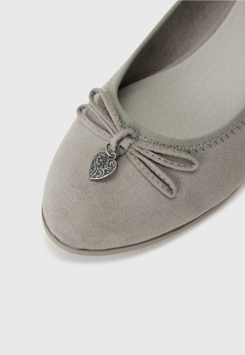 Bailarina de ante gris con punta redondeada, detalle de lazo decorativo y un pequeño charm en forma de corazón plateado. Forro interior suave y acentos cosidos.