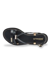 Black leather sandal with multiple straps, gold-toned detailing, cushioned footbed, and beige accents. Stitching outlines the sole.