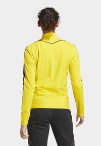 Gele lange mouwen sportshirt met een gemoleerde afwerking, zwarte accenten langs de schouders en een hoge kraag.
