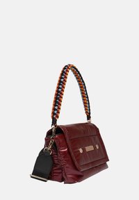 Bordeaux gekwilt tas met een gestructureerde afwerking, voorzien van een gevlochten handvat in oranje, blauw en zwart, en accenten in goudkleurig hardware.