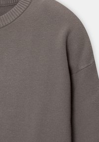Grau gestrickter Pullover mit einem runden Halsauschnitt und geripptem Kragen. Die Textur ist weich und glatt und zeigt ein nahtloses Schulterdesign.