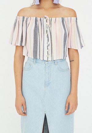 Frau trägt ein pastell gestreiftes Schulterfreies Crop-Top mit Knöpfen vorne und einen hellblauen Jeansrock mit Fronthaarschnitt.