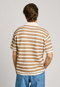 Striped short-sleeve polo shirt featuring alternating colors of cream, orange, and green. Soft knit texture with a flat collar.