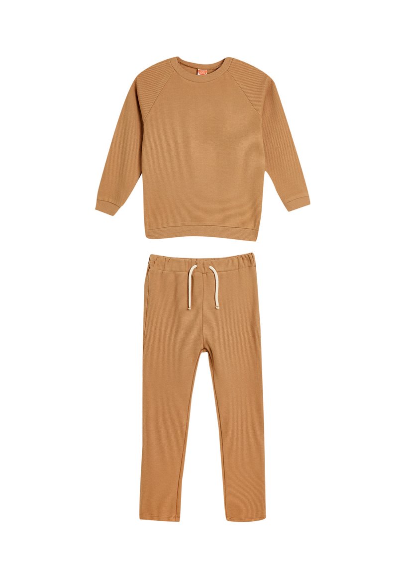 Beige bomullströja med ribbad textur och långa ärmar, i kombination med matchande ribbade sweatpants med elastisk midja och dragsko.
