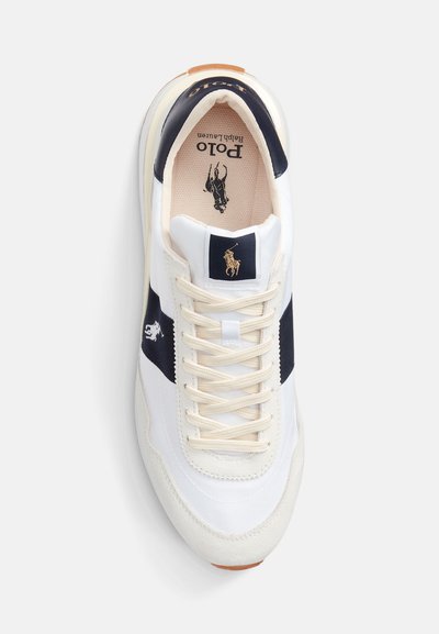 Sneaker bianca con accenti blu navy, superficie texturizzata e logo dorato. Presenta una chiusura con lacci, collo imbottito e una suola in gomma liscia.