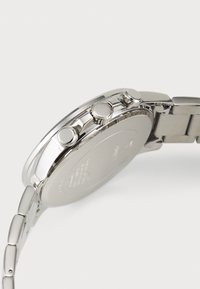 Montre en acier inoxydable argenté avec un boîtier rond, trois boutons-poussoirs sur le côté et un bracelet à maillons. Surface lisse avec une finition polie.
