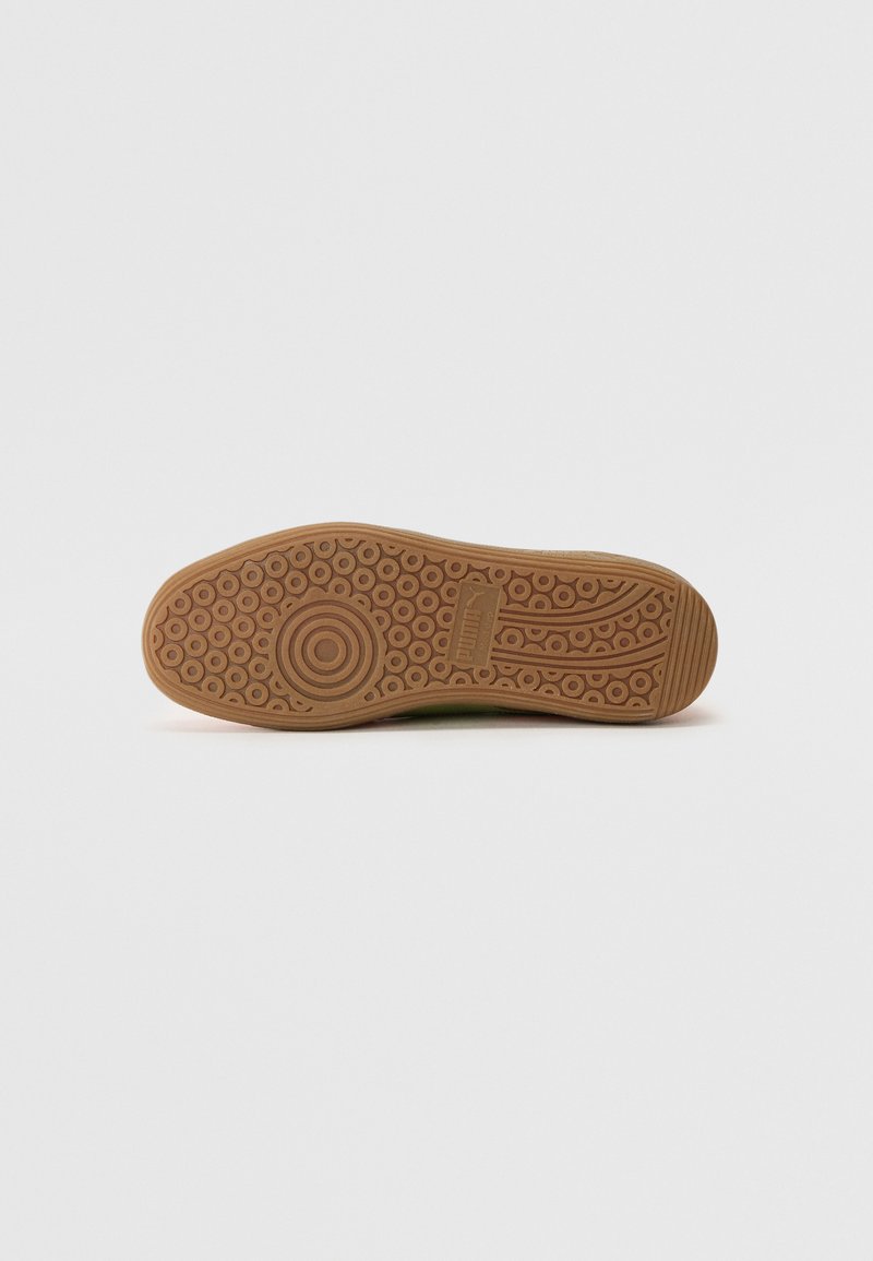 Semelle de chaussure avec une surface en caoutchouc marron texturé présentant des motifs circulaires et des rainures pour l'adhérence, s'effilant vers un bout arrondi.