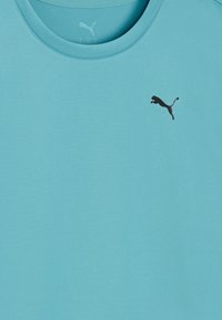 Φωτεινό μπλε μπλουζάκι με στρογγυλή λαιμόκοψη και μικρό μαύρο λογότυπο Puma στην επάνω αριστερή περιοχή του στήθους.