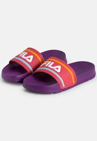 Violetti kumiset liukuvarpaat, joissa on leveä punainen hihna, jossa on valkoinen "FILA"-logo ja värikkäät raidat oranssina ja vaaleansinisenä. Teksturoitu pohja.