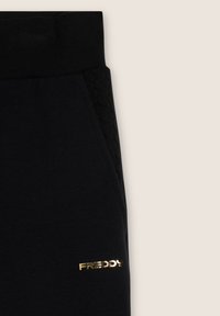 Pantalones deportivos negros con un panel lateral texturizado y un logo dorado en el muslo. Hechos de tela suave con una cintura elástica.