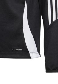 Melnā sporta krekls ar baltām sānu akcentiem, izgatavots no teksturētas auduma. Uz apakšējā malā atrodas "AEROREADY" logo, un plecu daļā ir trīs baltas svītras.